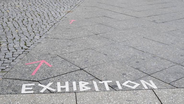 Schriftzug EXHIBITION (Ausstellung) auf einem Gehweg in Berlin-Prenzlauer Berg