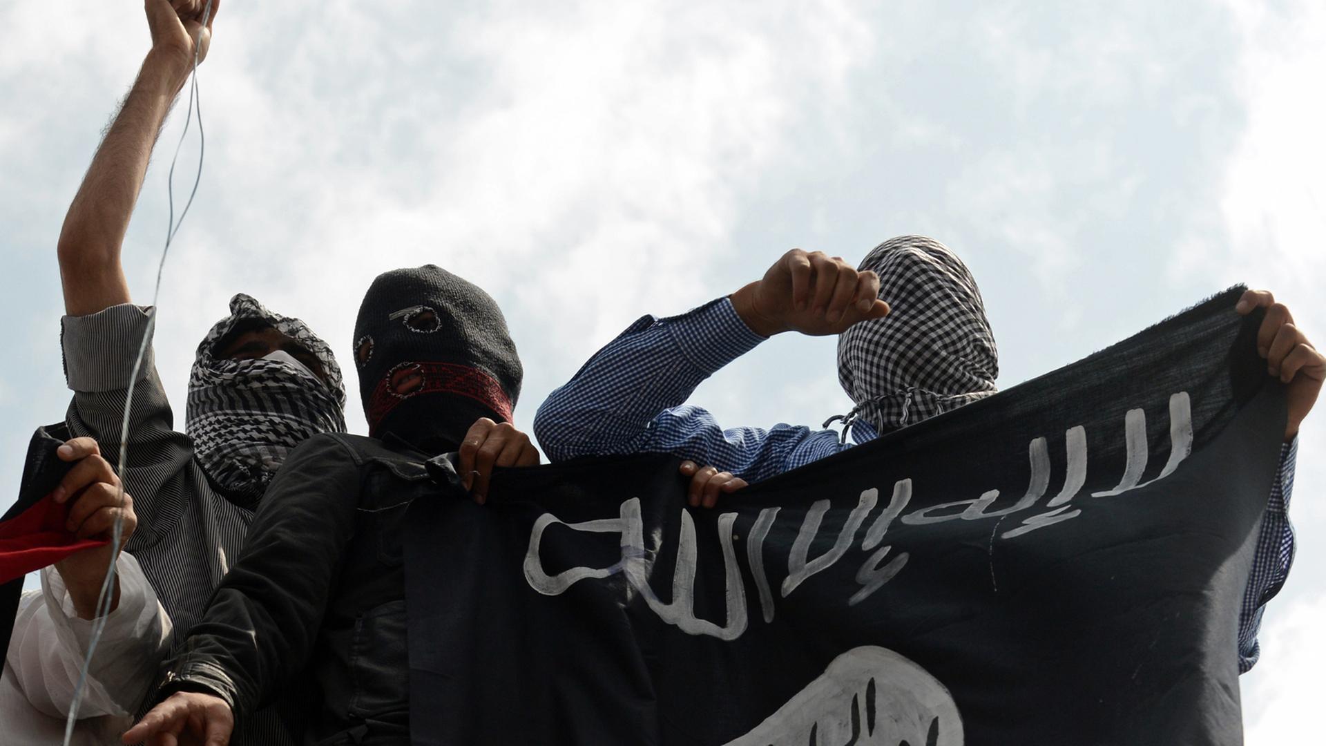 Unterstützer der Extremistenmiliz Islamischer Staat (IS) mit Fahne. Unterstützer der Extremistenmiliz Islamischer Staat (IS) mit Fahne.