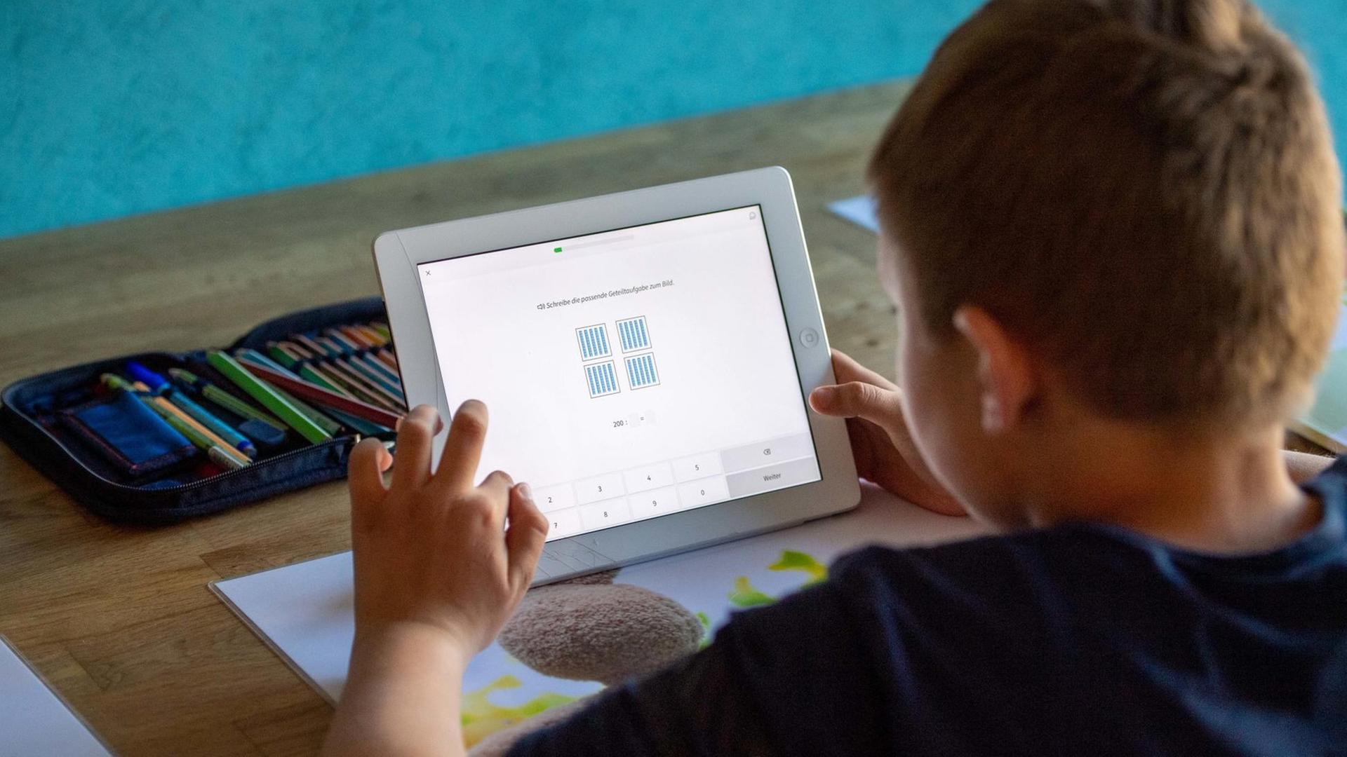 Ein Junge sitzt mit einem Tablet an seinem Schreib-Tisch. Ein Junge sitzt mit einem Tablet an seinem Schreib-Tisch.