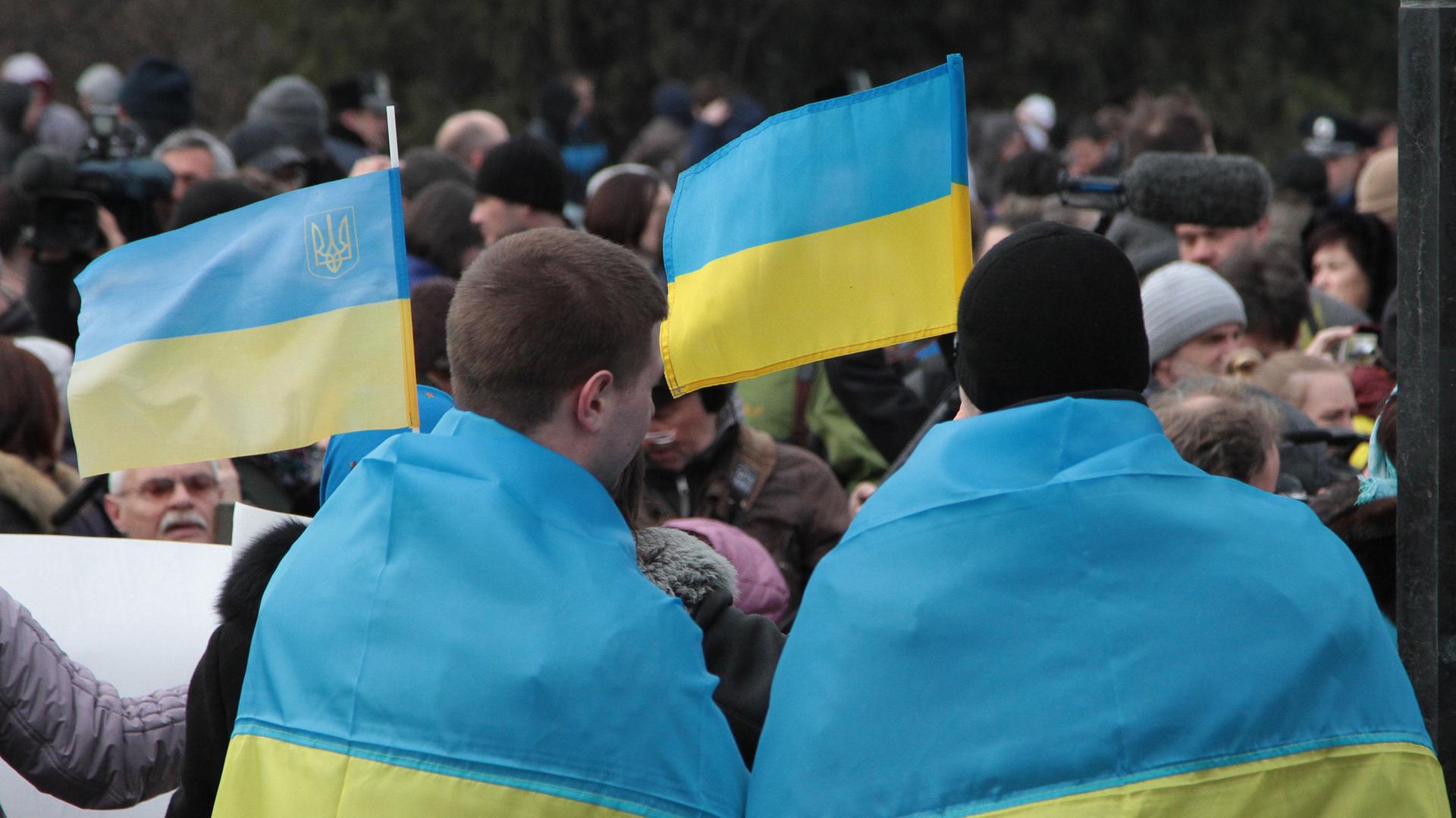 Ukrainer protestieren in Simferopol auf der Krim gegen das bevorstehende Referendum. Sie tragen die ukrainische Flagge über ihren Schultern. Ukrainer protestieren in Simferopol auf der Krim gegen das bevorstehende Referendum. Sie tragen die ukrainische Flagge über ihren Schultern.