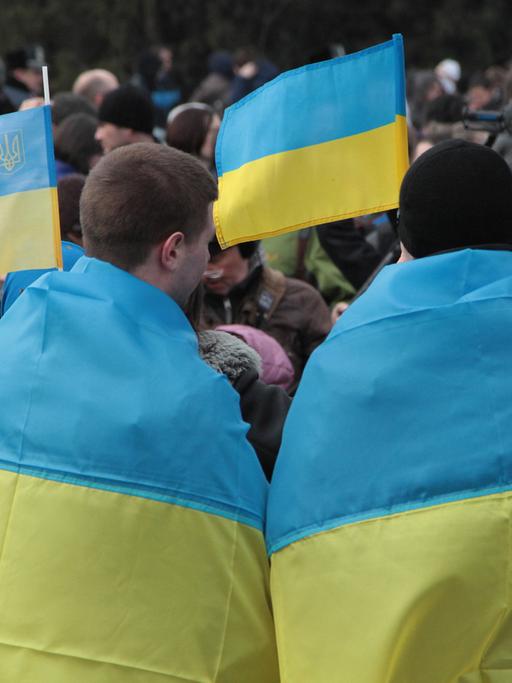 Ukrainer protestieren in Simferopol auf der Krim gegen das bevorstehende Referendum. Sie tragen die ukrainische Flagge über ihren Schultern.