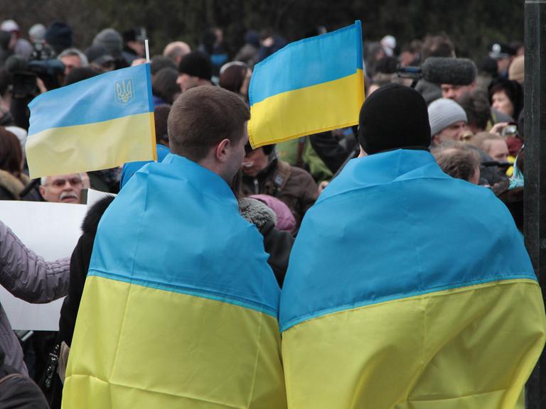 Ukrainer protestieren in Simferopol auf der Krim gegen das bevorstehende Referendum. Sie tragen die ukrainische Flagge über ihren Schultern.