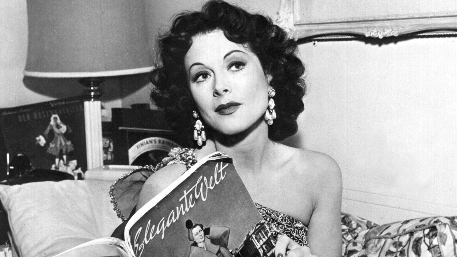 Die amerikanische Schauspielerin Hedy Lamarr blättert in der "Eleganten Welt" (undatiert). Hedy Lamarr, die in den 30er Jahren als "exotischer Sex-Star" in Hollywood Ruhm erlangte, ist am 19.1.2000 tot in ihrem Haus bei Orlando in Florida aufgefunden worden. Die gebürtige Österreicherin starb im Alter von 86 Jahren. Lamarr bekam aus Hollywood erste Rollenangebote, nachdem sie 1933 für einen Moment fast nackt in dem tschechischen Film "Ekstase" zu sehen gewesen war. Viele Jahre war die Ehefrau eines österreichischen Waffenhändlers danach in den USA auf die Rolle der "schönen Exotin" festgelegt. Sie war aber auch als Erfinderin tätig. 1942 erhielt Lamarr das Patent für eine spezielle Funktechnik. Das Verfahren wurde später bei der Entwicklung von Handys genutzt. Die amerikanische Schauspielerin Hedy Lamarr blättert in der "Eleganten Welt" (undatiert). Hedy Lamarr, die in den 30er Jahren als "exotischer Sex-Star" in Hollywood Ruhm erlangte, ist am 19.1.2000 tot in ihrem Haus bei Orlando in Florida aufgefunden worden. Die gebürtige Österreicherin starb im Alter von 86 Jahren. Lamarr bekam aus Hollywood erste Rollenangebote, nachdem sie 1933 für einen Moment fast nackt in dem tschechischen Film "Ekstase" zu sehen gewesen war. Viele Jahre war die Ehefrau eines österreichischen Waffenhändlers danach in den USA auf die Rolle der "schönen Exotin" festgelegt. Sie war aber auch als Erfinderin tätig. 1942 erhielt Lamarr das Patent für eine spezielle Funktechnik. Das Verfahren wurde später bei der Entwicklung von Handys genutzt.