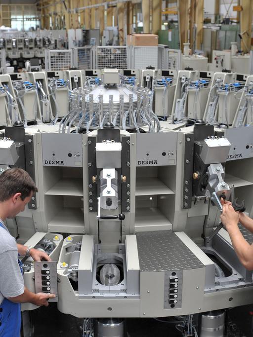 Mitarbeiter der Firma DESMA in Achim schrauben in der Fertigungshalle an einer neuen Schuhbesohlungsmaschine. Statt Sohle und Schuhschaft wie üblich miteinander zu vernähen, spritzen Roboter flüssigen Kunststoff direkt an den Schuhschaft.