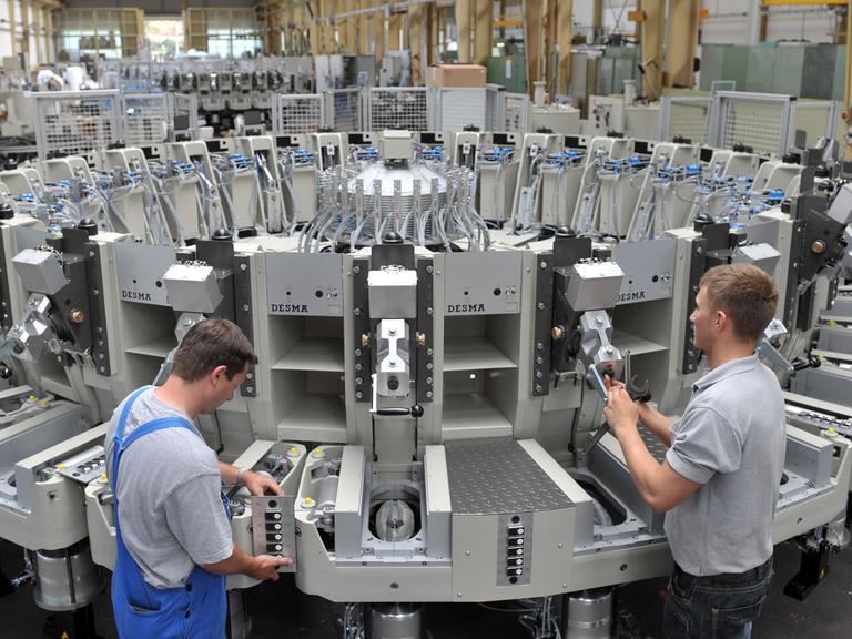 Mitarbeiter der Firma DESMA in Achim schrauben in der Fertigungshalle an einer neuen Schuhbesohlungsmaschine. Statt Sohle und Schuhschaft wie üblich miteinander zu vernähen, spritzen Roboter flüssigen Kunststoff direkt an den Schuhschaft.