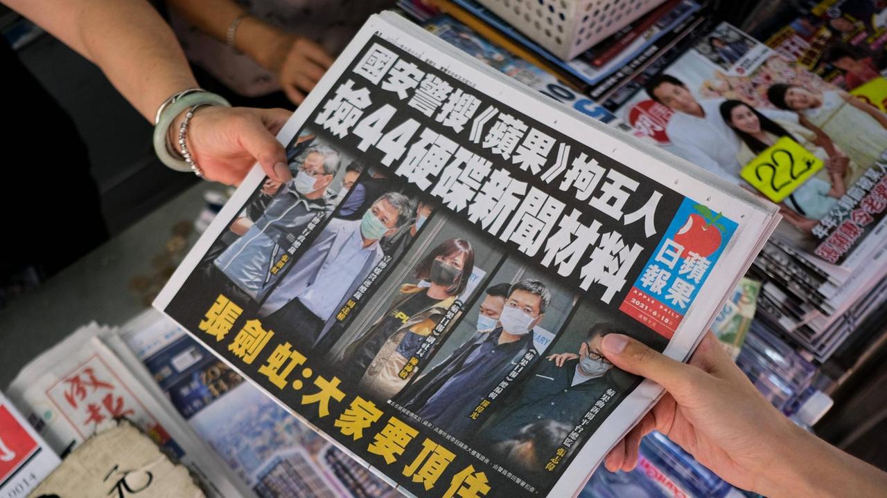 Die Hongkonger Tageszeitung Apple Daily wird an einem Kiosk von Verkäuferin zu Kundin gereicht. Die Hongkonger Tageszeitung Apple Daily wird an einem Kiosk von Verkäuferin zu Kundin gereicht.