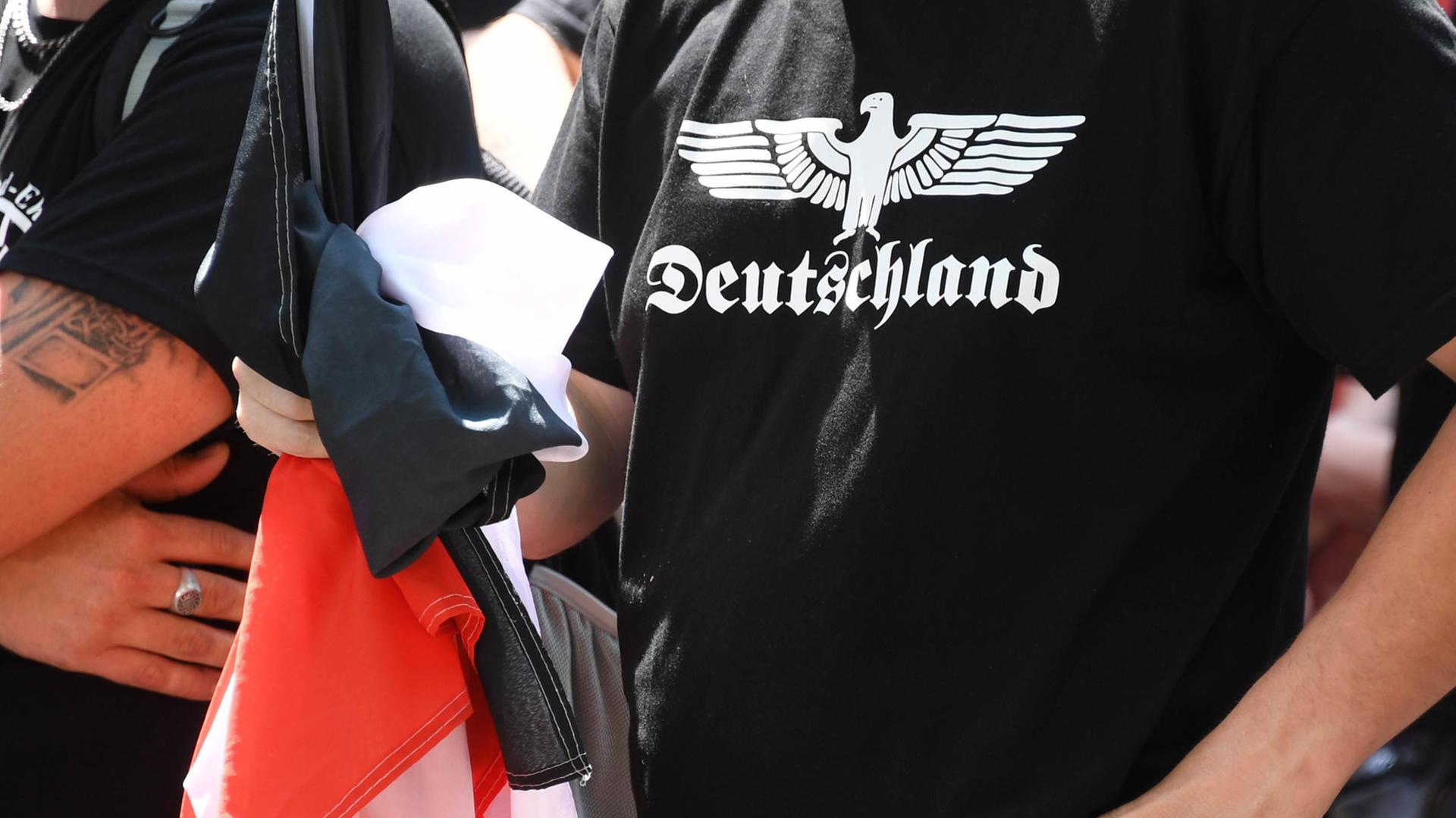 Ein Teilnehmer einer Demonstration von Rechtsextremen hält eine schwarz-weiß-rote Fahne in der Hand und trägt ein schwarzes T-Shirt mit der Aufschrift "Deutschland". Ein Teilnehmer einer Demonstration von Rechtsextremen hält eine schwarz-weiß-rote Fahne in der Hand und trägt ein schwarzes T-Shirt mit der Aufschrift "Deutschland".
