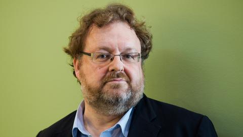 Der FAZ-Redakteur Jürgen Kaube, Man mit Brille und vor grüner Wand, in die Kamera blickend.