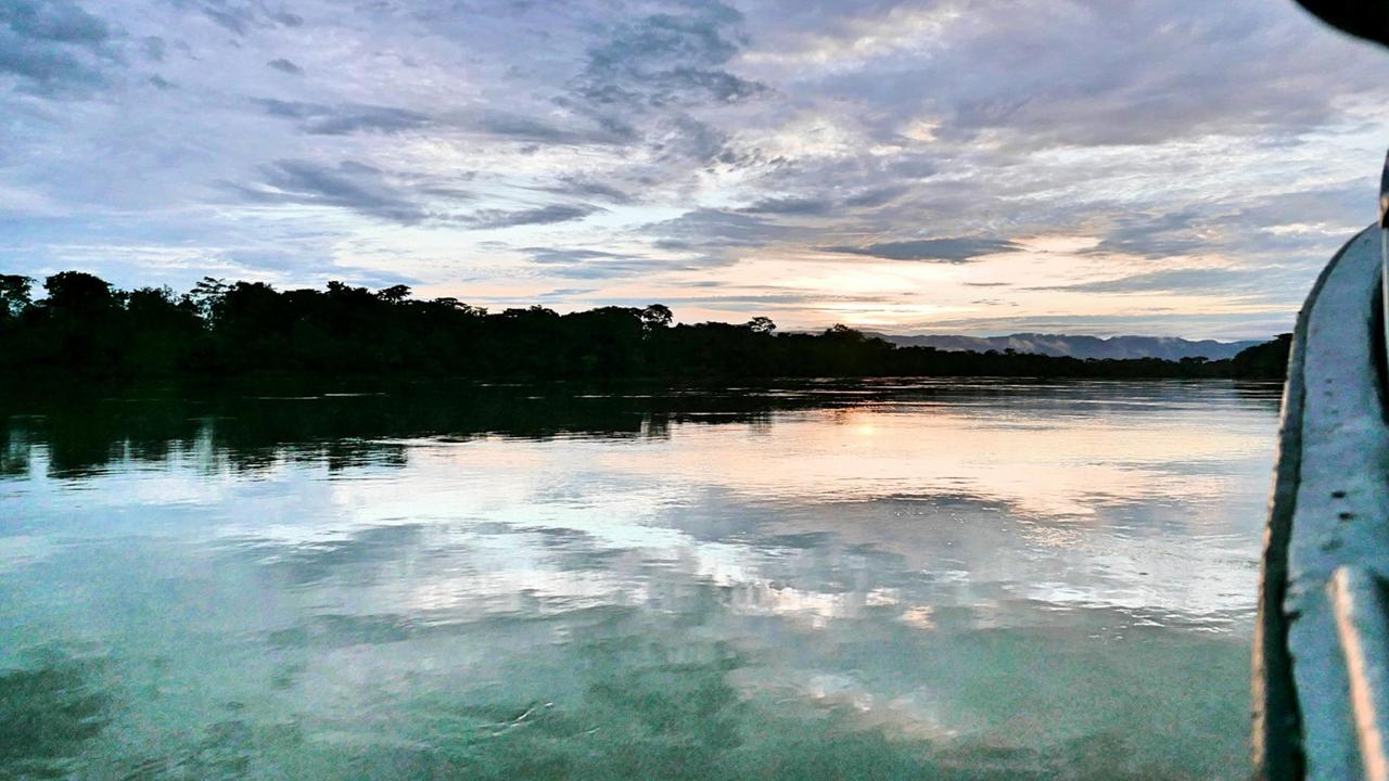 Der breite Fluss mit Regenwald am Ufer, tief hängende Wolken und eine gerade aufgehende Sonne. Der breite Fluss mit Regenwald am Ufer, tief hängende Wolken und eine gerade aufgehende Sonne.