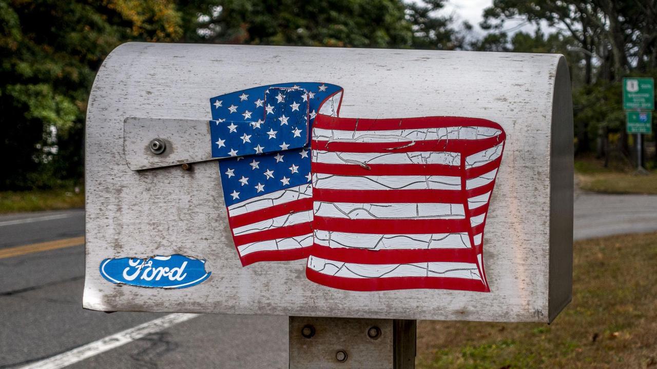 Ein typischer Briefkasten mit einer wehenden US-Flagge steht an einer Straße unweit von Boston, Massachusetts