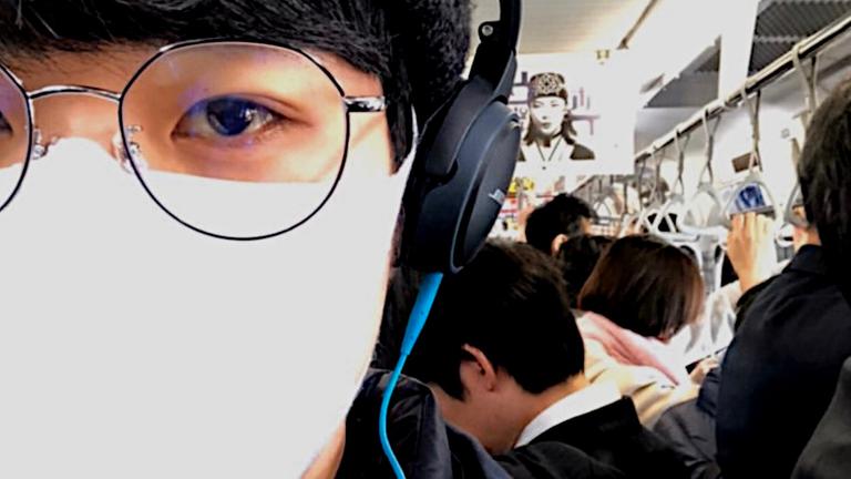 Selfie in einer U-Bahn: Ein junger Mann mit Mundschutz, Kopfhörern und Brille, daneben zahlreiche Fahrgäste Selfie in einer U-Bahn: Ein junger Mann mit Mundschutz, Kopfhörern und Brille, daneben zahlreiche Fahrgäste