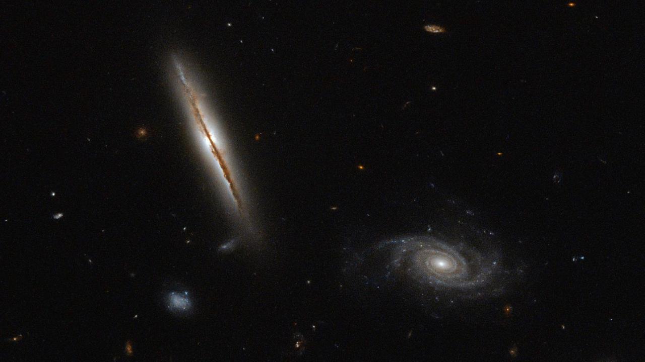 Zu sehen ist eine Aufnahme des Hubble Space Telescope von einer spiralförmigen Galaxie, die sich hell vom schwarzen Weltraum abhebt. Zu sehen ist eine Aufnahme des Hubble Space Telescope von einer spiralförmigen Galaxie, die sich hell vom schwarzen Weltraum abhebt.