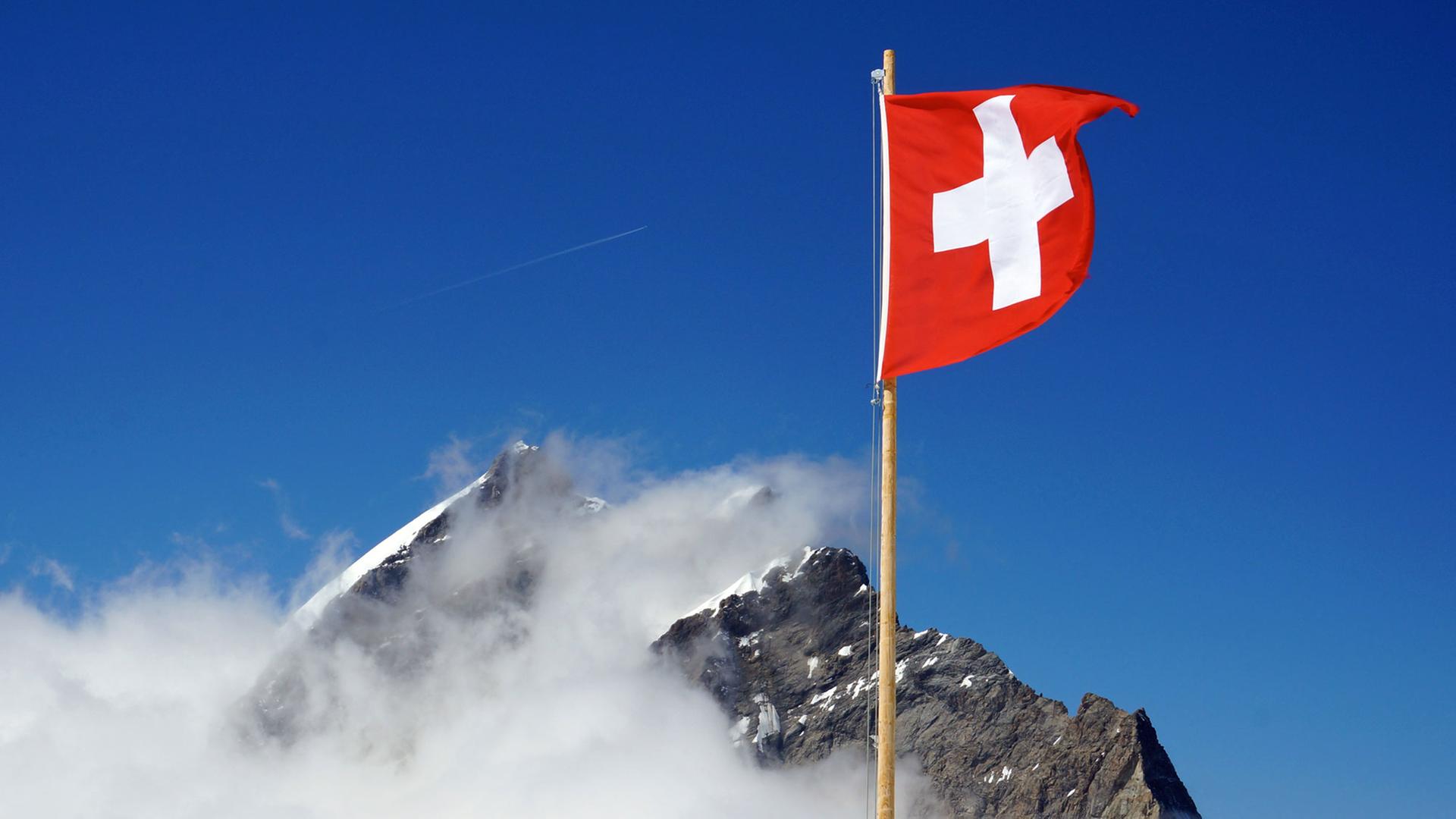 Die Schweizer Flagge weht nahe dem Jungfraujoch in den Berner Alpen Die Schweizer Flagge weht nahe dem Jungfraujoch in den Berner Alpen