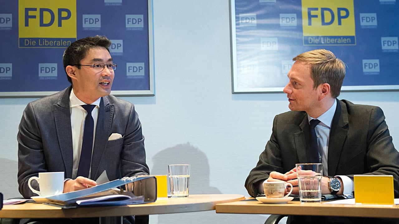 Philipp Rösler und Christian Lindner sitzen an zwei nebeneinanderstehenden Konferenztischen. Philipp Rösler und Christian Lindner sitzen an zwei nebeneinanderstehenden Konferenztischen.