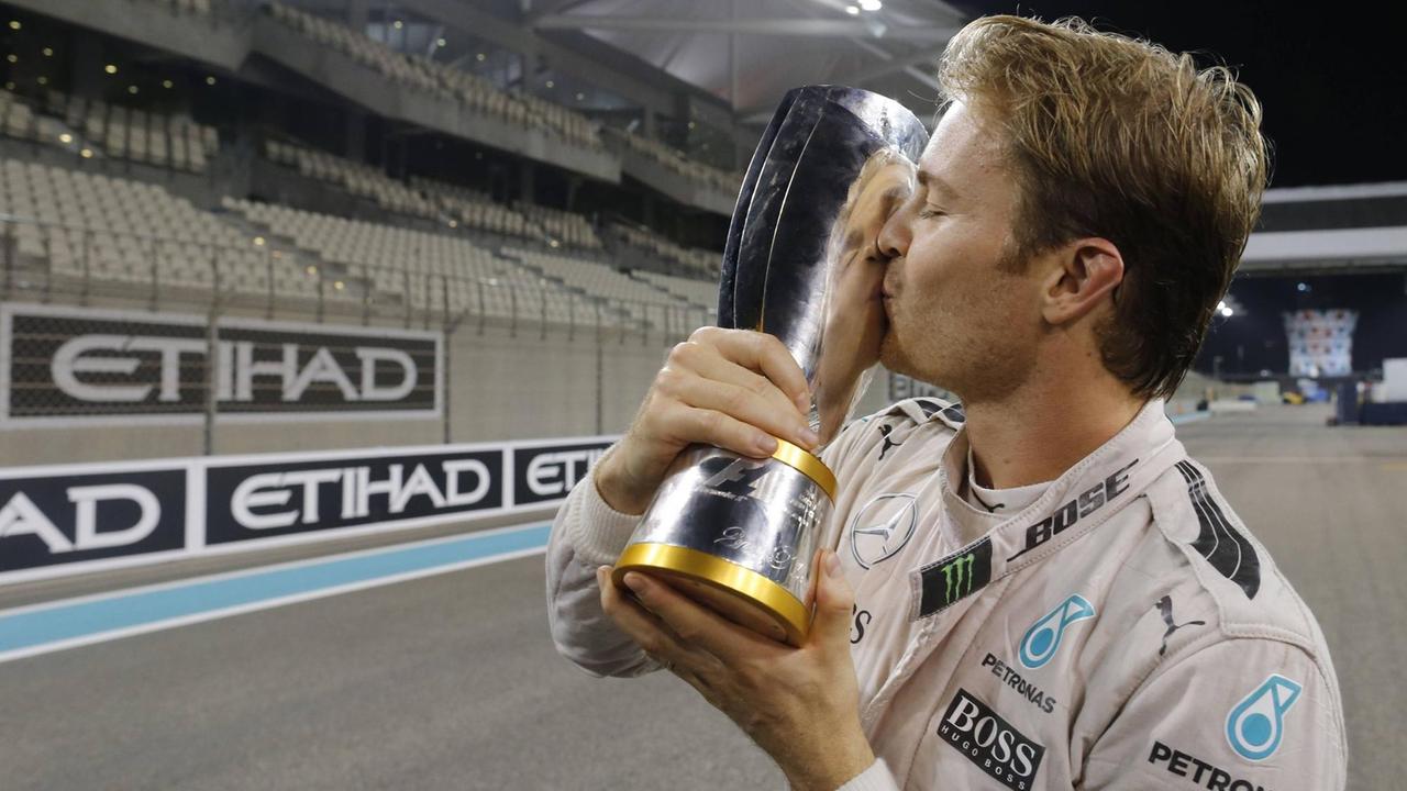 Formel-1-Rennfahrer Nico Rosberg hält nach dem Gewinn des WM-Titels den Pokal in Händen und küsst ihn zärtlich.