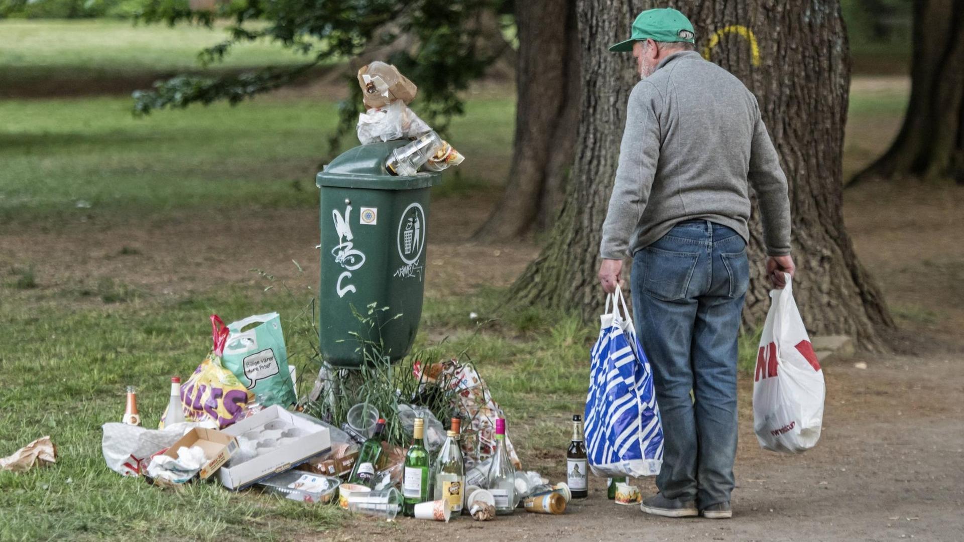 Farbfoto, ein alter Mann sammelt Flaschen vor einem städtischen Müllbehälter Farbfoto, ein alter Mann sammelt Flaschen vor einem städtischen Müllbehälter