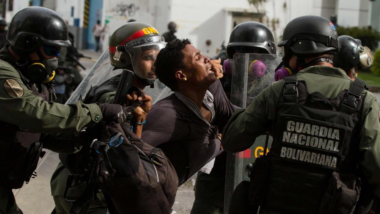 Polizisten nehmen einen Demonstranten in Caracas am Rande von Protesten gegen Präsident Maduro fest. Polizisten nehmen einen Demonstranten in Caracas am Rande von Protesten gegen Präsident Maduro fest.