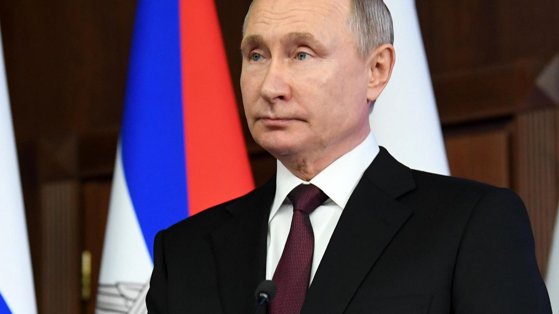 Putin in schwarzem Sacko vor der russischen Flagge Putin in schwarzem Sacko vor der russischen Flagge