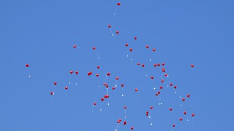 Fliegende rote Luftballons am blauen Himmel.
