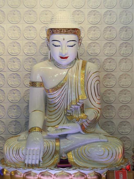 Buddha mit Abhaya Mudra, einer Geste, bei der Buddhas linke Hand nach oben geöffnet auf dem Schoß liegt, während die Fingerspitzen seiner rechten Hand den Boden berühren. Die Statue befindet sich in dem Fo Guang Shan Tempel in Bussy-Saint-Georges, Frankreich.