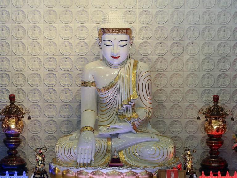 Buddha mit Abhaya Mudra, einer Geste, bei der Buddhas linke Hand nach oben geöffnet auf dem Schoß liegt, während die Fingerspitzen seiner rechten Hand den Boden berühren. Die Statue befindet sich in dem Fo Guang Shan Tempel in Bussy-Saint-Georges, Frankreich.