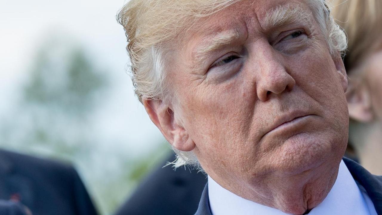Trump mit ernstem Blick vor weiteren Personen Trump mit ernstem Blick vor weiteren Personen