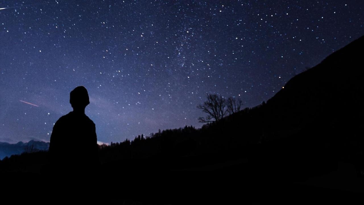 Ein Mann blickt in den Sternenhimmel.