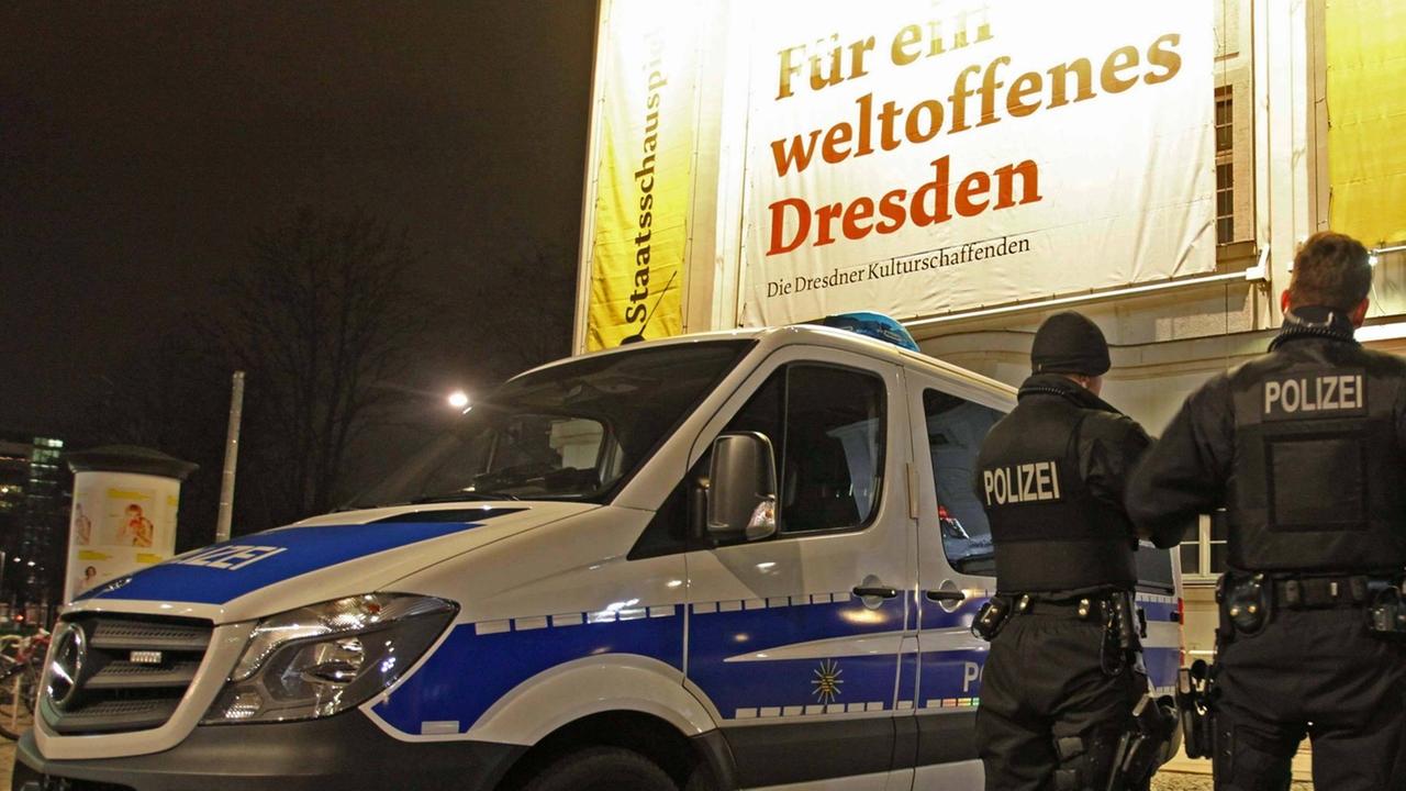 Drei Polizisten stehen in Dresden neben ihrem Einsatzwagen. Drei Polizisten stehen in Dresden neben ihrem Einsatzwagen.