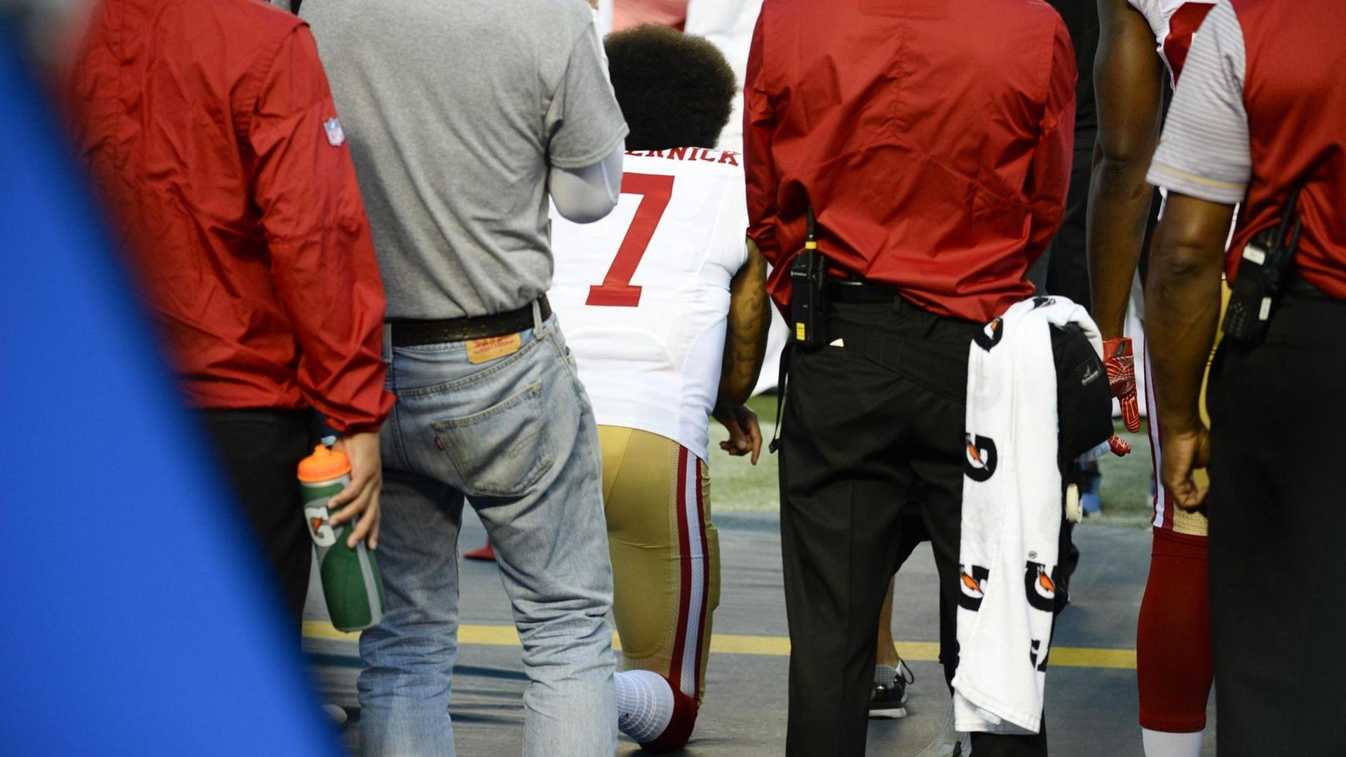 Der Quarterback der San Francisco 49ers, Colin Kaepernick, kniet während der Nationalhymne. Der Quarterback der San Francisco 49ers, Colin Kaepernick, kniet während der Nationalhymne.