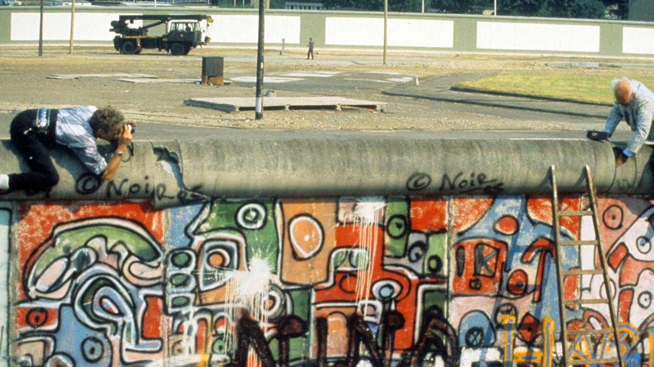 John Runnings demonstriert am 07.08.1986 mit einem Balanceakt gegen den Bau der Berliner Mauer vom 13. August 1961. Mit einem großen Vorschlaghammer führt der 69-jährige Amerikaner vor, was seiner Meinung nach mit dem Bauwerk zu tun sei.