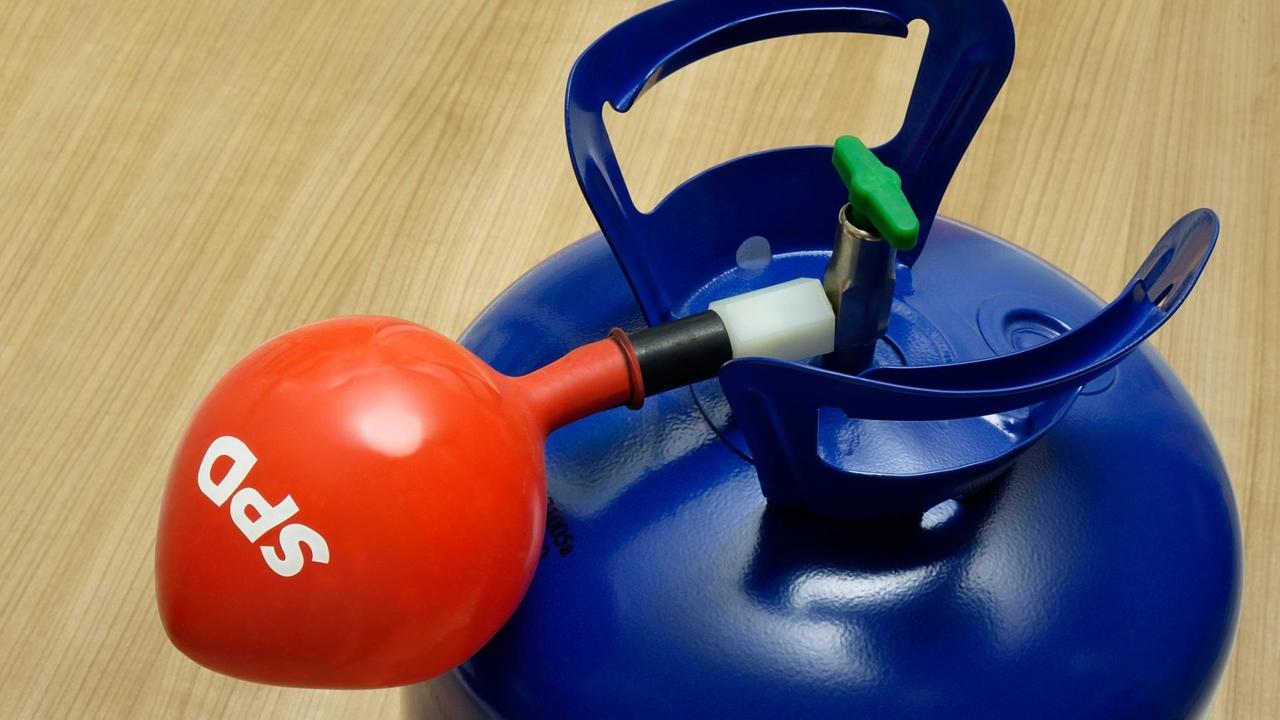 Das Bild zeigt einen roten SPD-Ballon, der an einer blauen Gasflasche hängt.