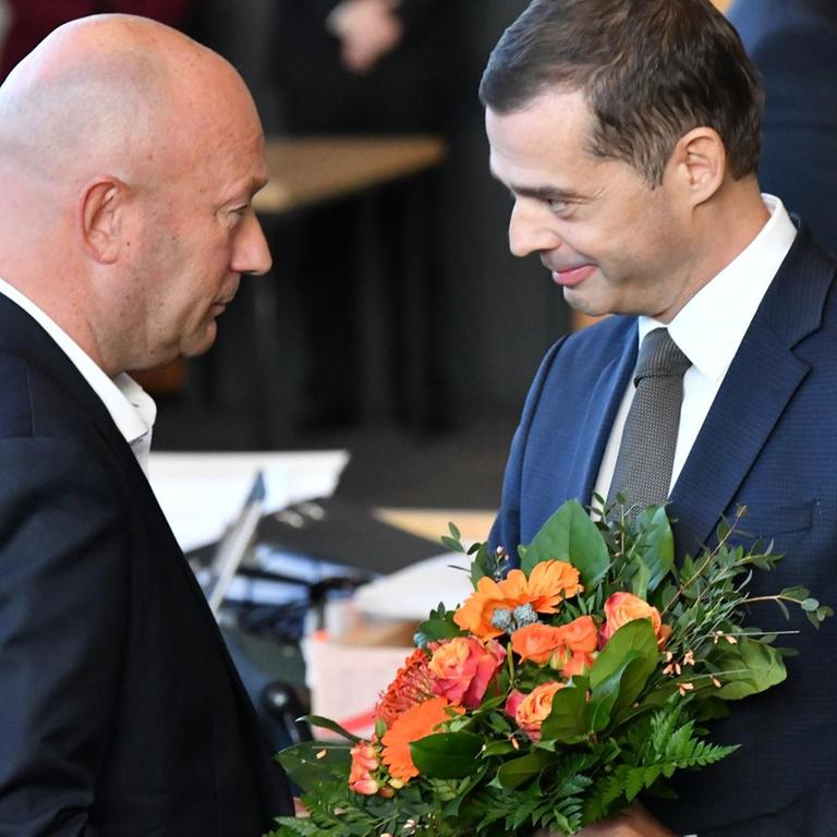 Mike Mohring, CDU-Fraktionschef, gratuliert Thomas Kemmerich (FDP), dem neuen Thüringer Ministerpräsidenten, mit einem Blumenstrauß.