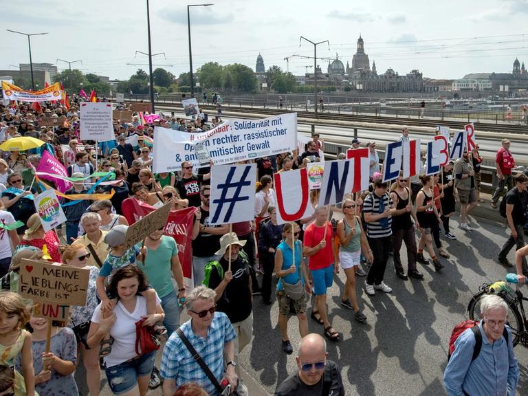 Anhänger des Bündnisses #unteilbar gehen während einer Demonstration über die Carolabrücke vor der historischen Altstadtkulisse von Dresden.