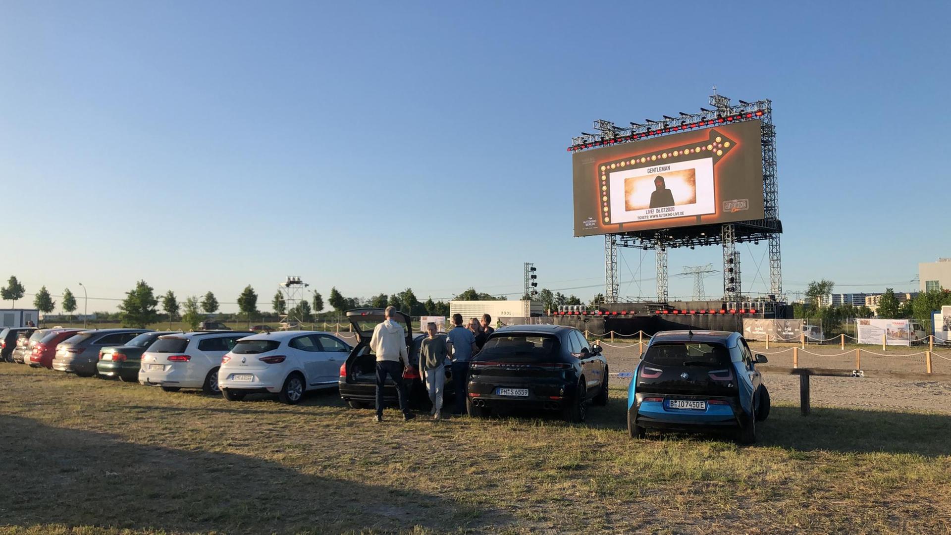 Aufnahme aus einem Autokino, mit Autos im Vordergrund und der Leinwand im Hintergrund, vor blauem Himmel. Aufnahme aus einem Autokino, mit Autos im Vordergrund und der Leinwand im Hintergrund, vor blauem Himmel.