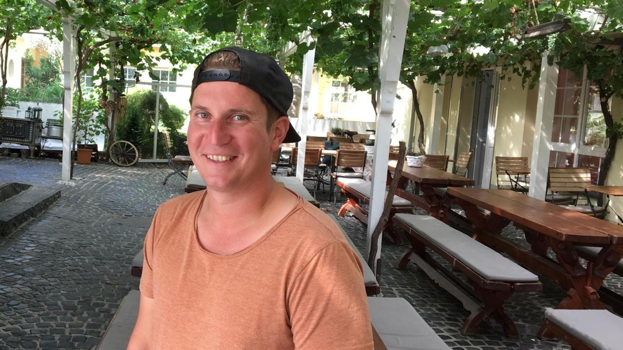 Der Winzer Max Schönleber mit umgedrehter Schirmmütze auf einer Terrasse mit Weinreben. Der Winzer Max Schönleber mit umgedrehter Schirmmütze auf einer Terrasse mit Weinreben.