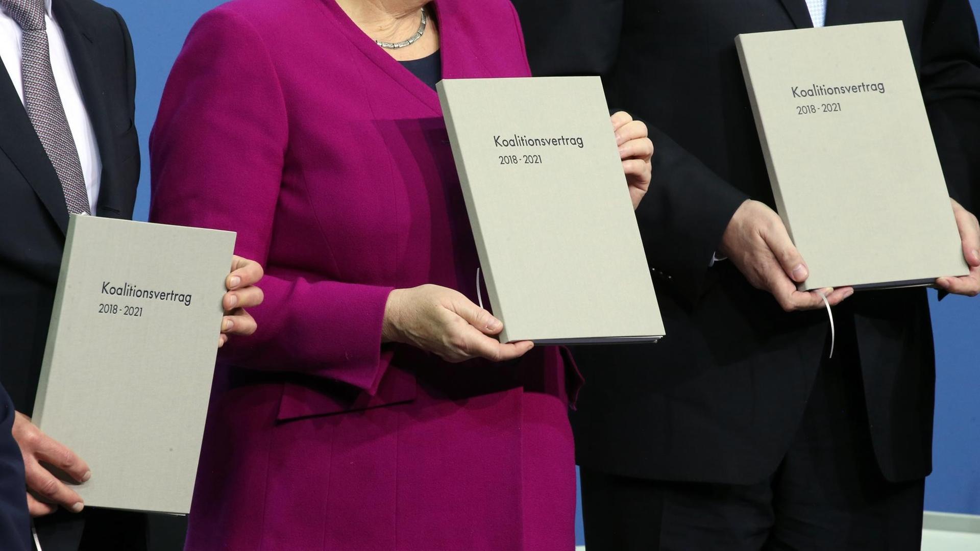 Das Foto vom 12.3.2018 zeigt Bundeskanzlerin Angela Merkel (M, CDU), den CSU-Vorsitzenden Horst Seehofer (r) und den damals kommissarischen SPD-Vorsitzenden Olaf Scholz. Sie halten den Koalitionsvertrag in den Händen.