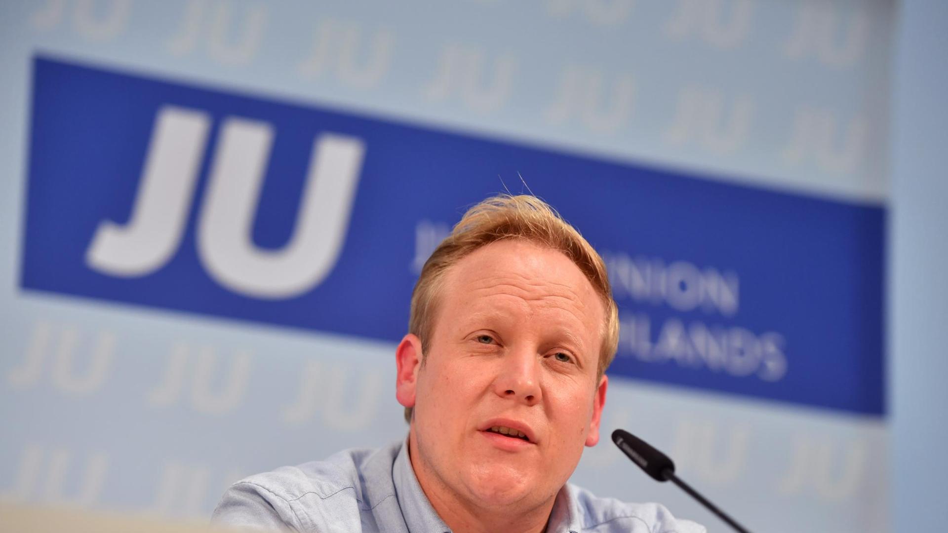Tilman Kuban spricht in ein Mikrofon, im Hintergrund ist das Logo der Jungen Union zu sehen. Tilman Kuban spricht in ein Mikrofon, im Hintergrund ist das Logo der Jungen Union zu sehen.