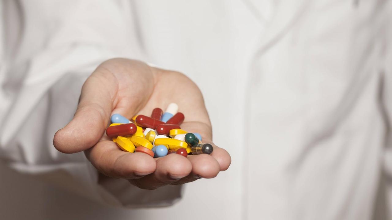 Ein Arzt hält Tabletten in der Hand. Ein Arzt hält Tabletten in der Hand.