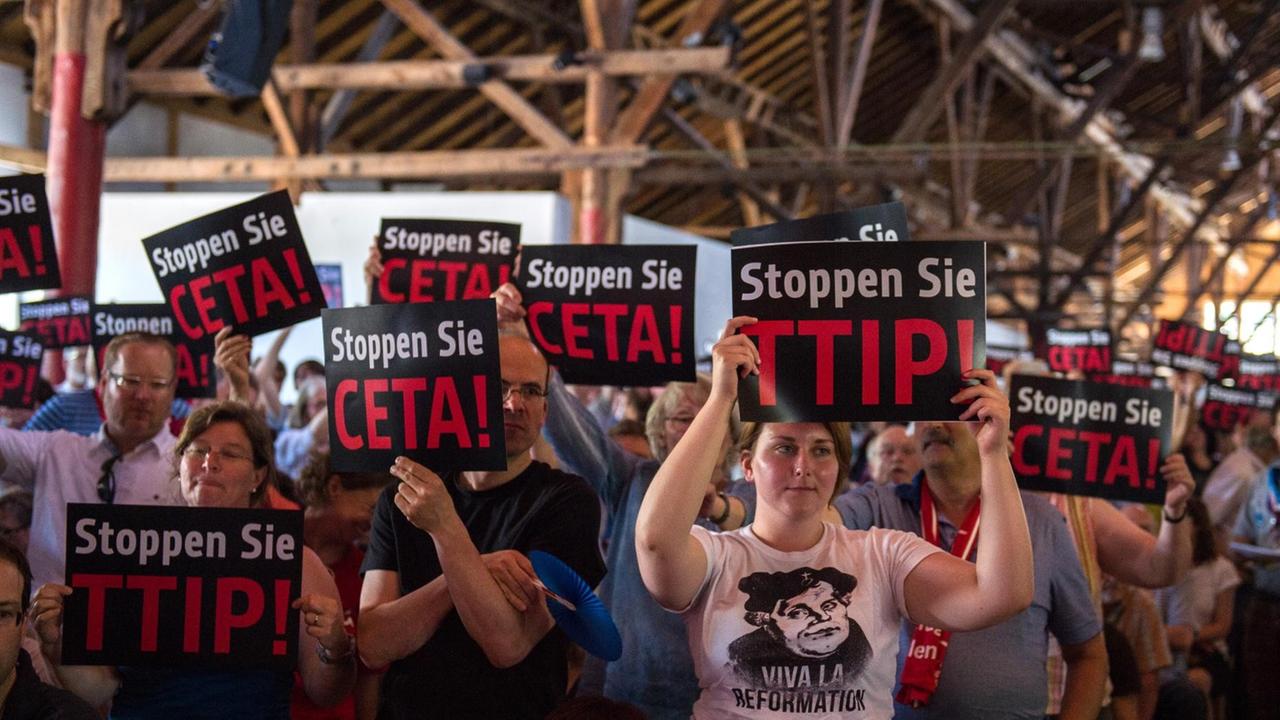 Kirchentagsteilnehmer halten bei einem Flashmob im Vorfeld einer Veranstaltung im Programm des deutschen evangelischen Kirchentags Schilder mit der Aufschrift "Stoppen Sie CETA!" und "Stoppen Sie TTIP" Kirchentagsteilnehmer halten bei einem Flashmob im Vorfeld einer Veranstaltung im Programm des deutschen evangelischen Kirchentags Schilder mit der Aufschrift "Stoppen Sie CETA!" und "Stoppen Sie TTIP"