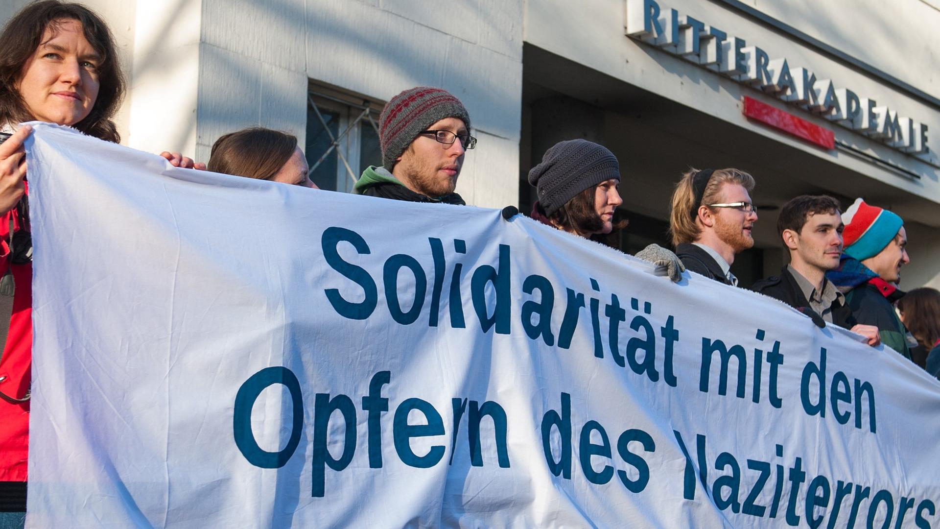 Menschen mit einem Banner mit der Aufschrift "Solidarität mit den Opfern des Naziterrors" in den Händen stehen am 21.04.2015 vor der zum Gerichtssaal umfunktionierten Ritterakademie in Lüneburg (Niedersachsen). 70 Jahre nach Ende der Nazi-Diktatur steht der frühere SS-Mann Oskar Gröning in Lüneburg vor Gericht. Die Anklage wirft ihm Beihilfe zum Mord im Vernichtungslager Auschwitz vor - in mindestens 300.000 Fällen. Menschen mit einem Banner mit der Aufschrift "Solidarität mit den Opfern des Naziterrors" in den Händen stehen am 21.04.2015 vor der zum Gerichtssaal umfunktionierten Ritterakademie in Lüneburg (Niedersachsen). 70 Jahre nach Ende der Nazi-Diktatur steht der frühere SS-Mann Oskar Gröning in Lüneburg vor Gericht. Die Anklage wirft ihm Beihilfe zum Mord im Vernichtungslager Auschwitz vor - in mindestens 300.000 Fällen.