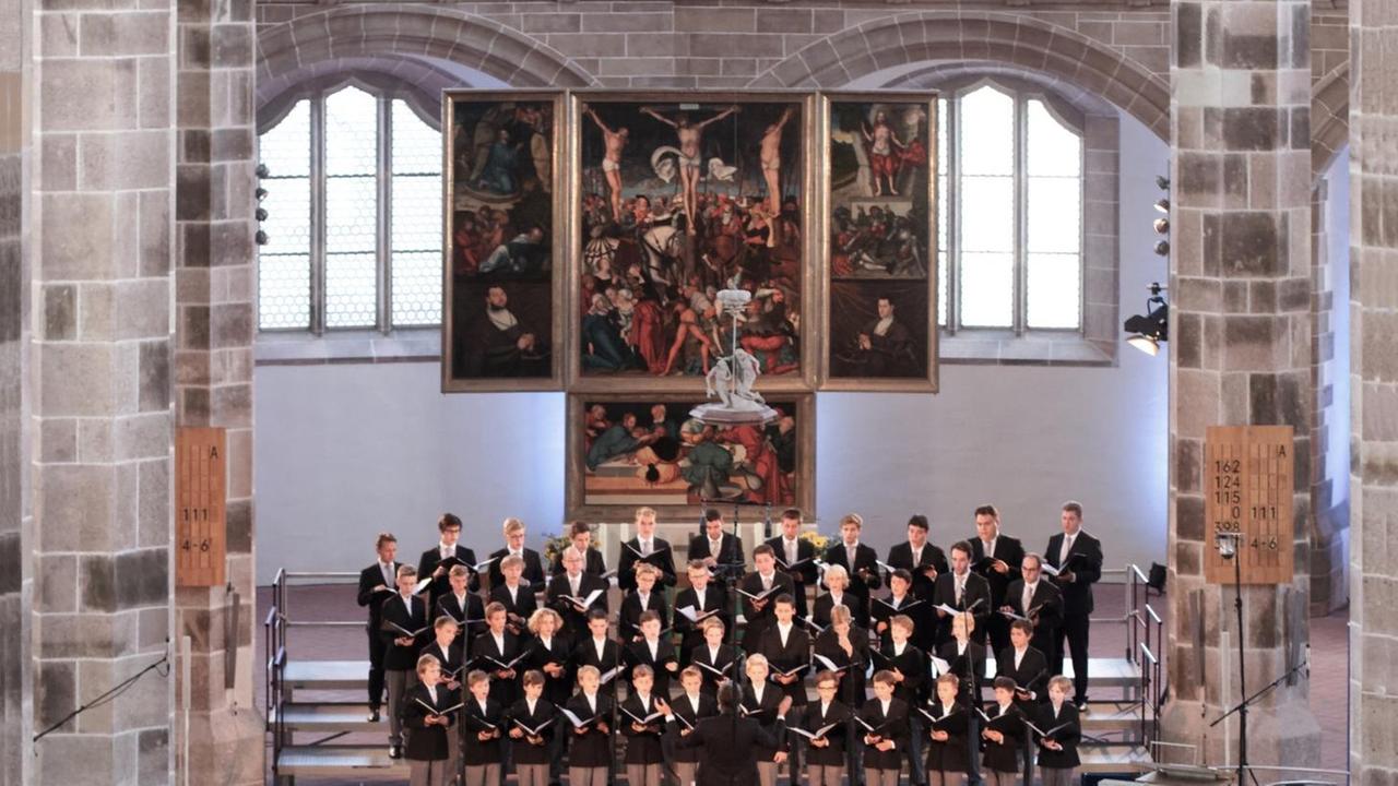 Ein Knabenchor steht im Altarraum einer großen Kirche und singt. Ein Knabenchor steht im Altarraum einer großen Kirche und singt.