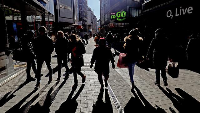 Menschen in der Fußgängerzone "Hohe Straße" in Köln werfen in der Mittagssonne lange Schatten.