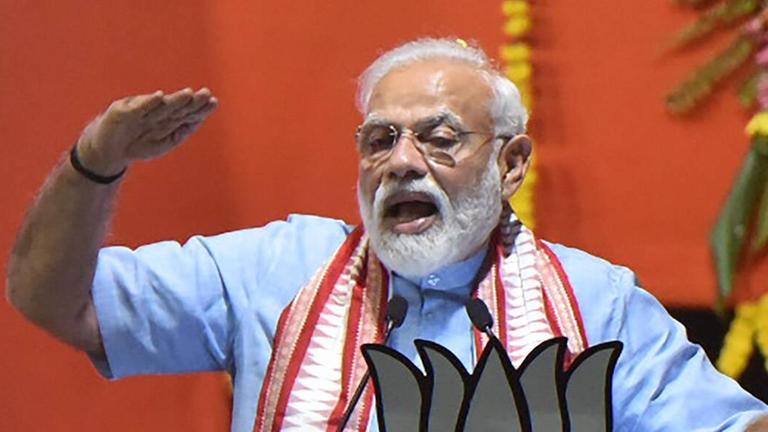 Narendra Modi steht an einem Rednerpult und gestikuliert. Narendra Modi steht an einem Rednerpult und gestikuliert.