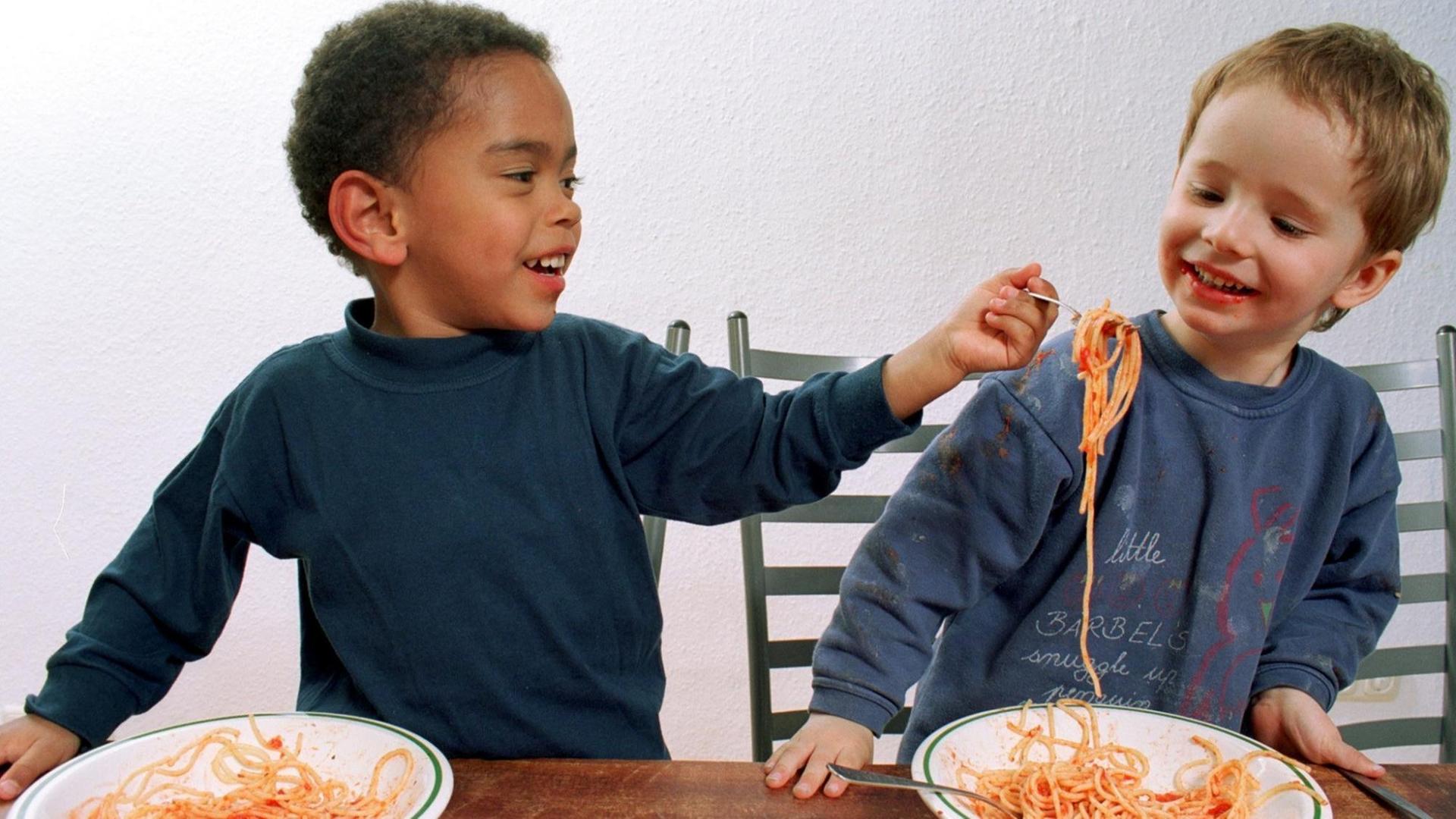 Zwei Jungen haben Spaß beim gemeinsamen Spaghetti-Essen. Zwei Jungen haben Spaß beim gemeinsamen Spaghetti-Essen.