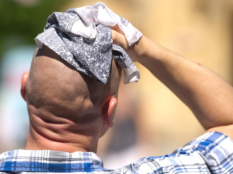 Klimawandel: Deutschland wird mehr Hitzetage bekommen; das Bild zeigt einen Mann von hinten, der ein Handtuch auf seine verschwitzte Glatze drückt...