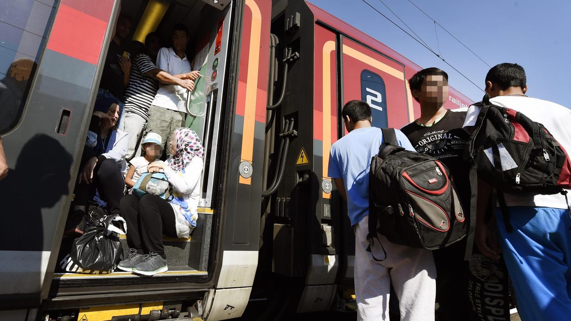 Flüchtlinge versuchen in den Zug nach Wien zu gelangen, in den Eingängen sitzen Menschen.