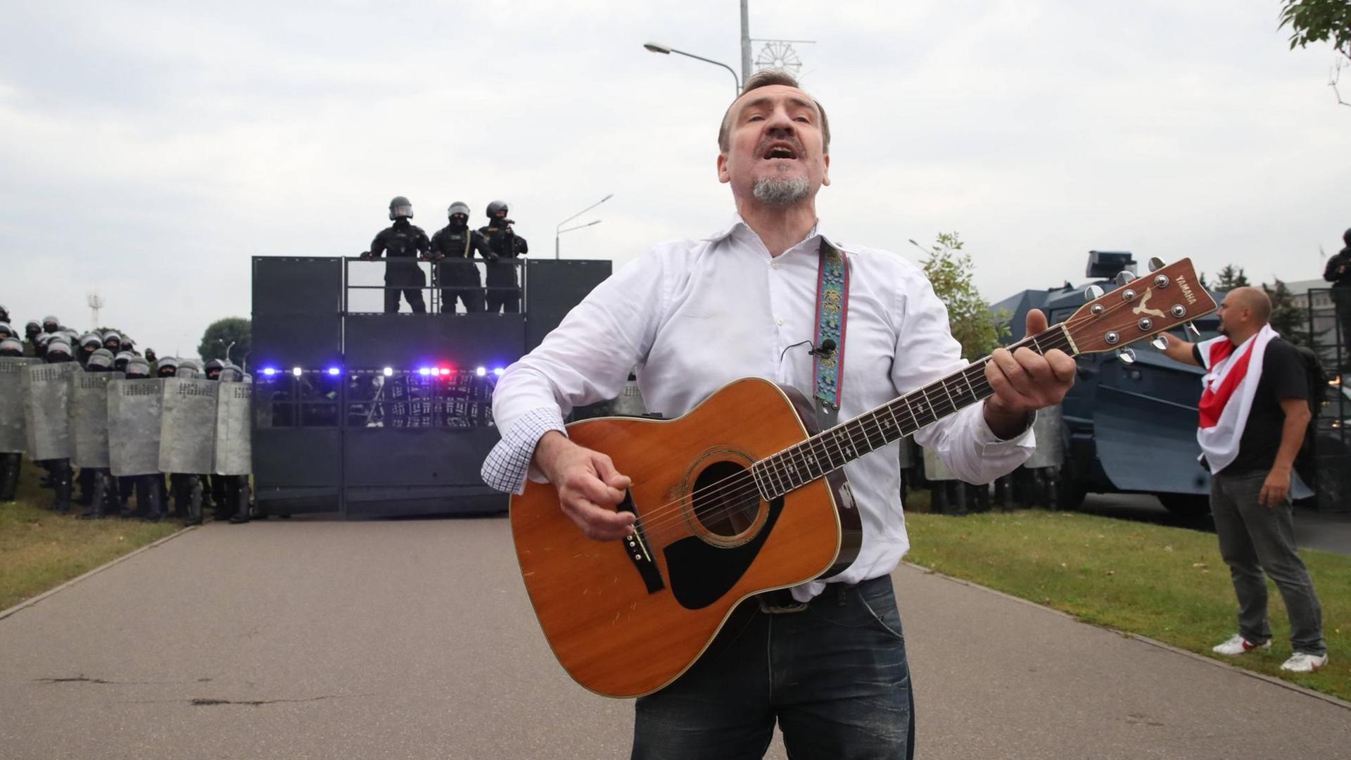 Der Gitarrist Pit Pawlow der belarussischen Band "N.R.M." steht mit einer Gitarre vor einer Polizeibarrikade. Der Gitarrist Pit Pawlow der belarussischen Band "N.R.M." steht mit einer Gitarre vor einer Polizeibarrikade.