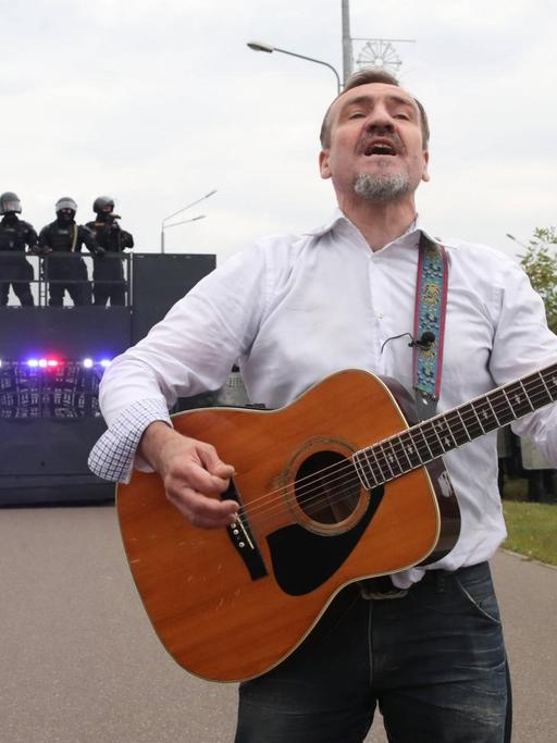 Der Gitarrist Pit Pawlow der belarussischen Band "N.R.M." steht mit einer Gitarre vor einer Polizeibarrikade.