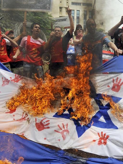Im Libanon zünden Menschen ein israelische Fahne an
