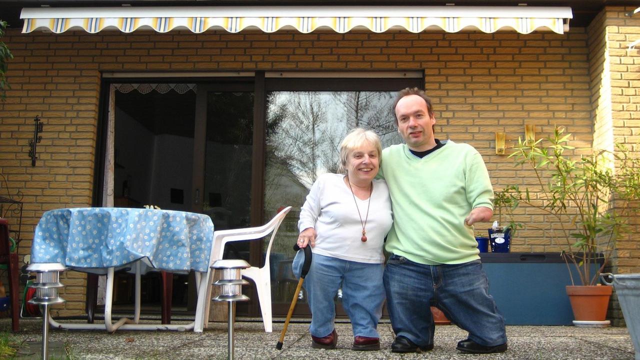 Eine Frau und ein Mann stehen auf einer Terrasse und halten sich im Arm. Eine Frau und ein Mann stehen auf einer Terrasse und halten sich im Arm.